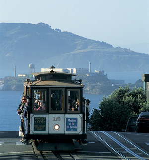 A photo of tourists riding a San Francisco cable car.
