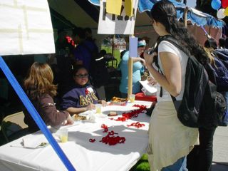 Three peer educatoA student approaches the table where red ribbons are being distributed