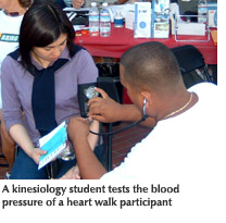 Photo of a kinesiology student testing the blood pressure of a heart walk participant