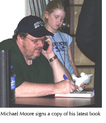 Photo of Michael Moore signing a copy of his latest book at the SFSU event