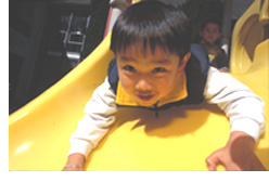 Photo of a young Head Start boy going down a plastic slide head first