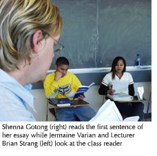 Photo of student Shenna Gotong reading the first sentence of her essay while student Jermaine Varian and Lecturer Brian Strang look at the class reader