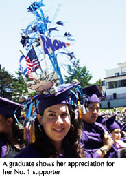 Photo of a graduate with a cap decorated with an American flag, a banner that says "mom," and other colorful items