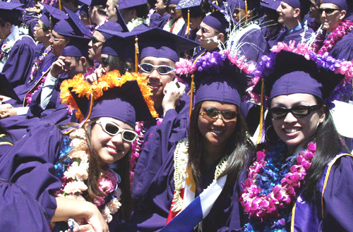 Photo of three women graduates in their purple graduation robes and caps decorated with flowers
