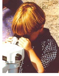 Photo of a young boy looking through a microscope