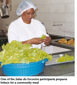 Photo of a woman who is one of the Salao do Encontro participants preparing lettuce for a community meal