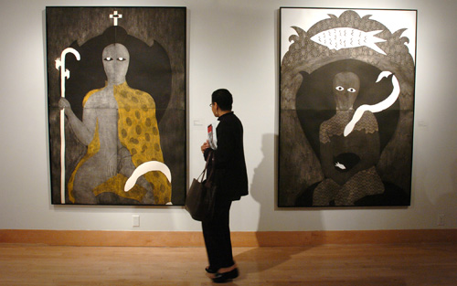 Photo of a gallery visitor looking at two works from the AfroCuba exhibit