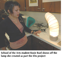 Photo of a School of the Arts student standing next to the lamp she created