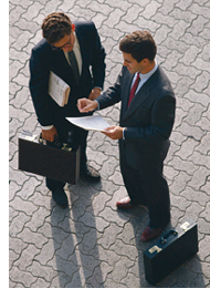 Photo of two men with briefcases looking at a document
