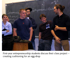 Photo of a group of entrepreneurship students discussing their class project, creating cushioning for an egg-drop