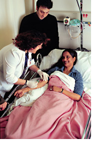 Photo of a female nurse tending to a young woman in a hospital bed