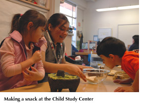 Photo of a boy and a girl helping a Child Study Center teacher make a snack