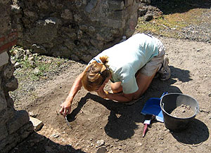 A photograph of a student removing soil in an archeological dig as part of San Francisco State's archeological field school in Pompeii.