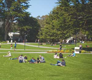 Photo of the campus quad with students sitting on the lawn