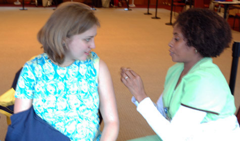 A student prepares to receive an H1N1 vaccine from a nursing student.