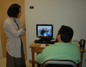 A photo of Professor Yu with a parent who is watching his young son's progress from a remote computer screen.