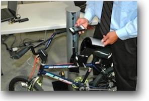 A photo of a student demonstrating a Bluetooth enabled bicycle lock.