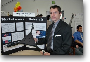 A photo of Mark Gianni holding a tricopter made of foam core board.