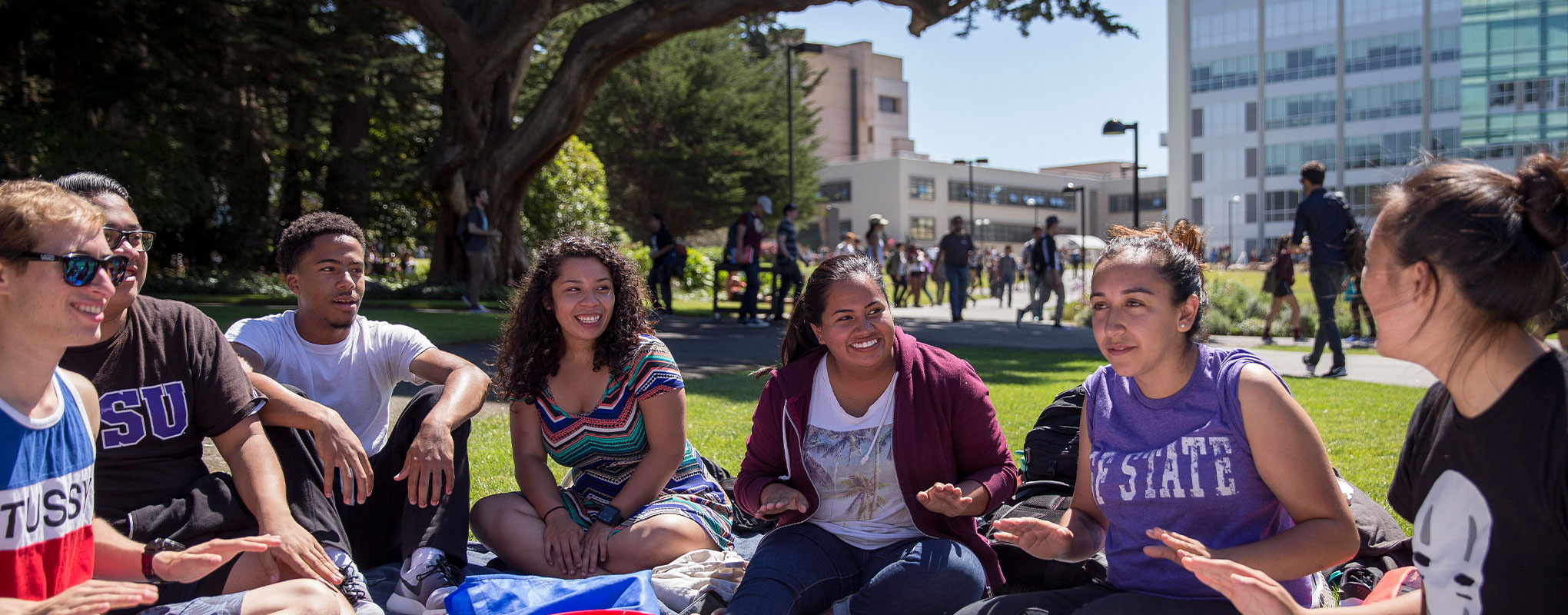 Students gather in the green quad laughing 