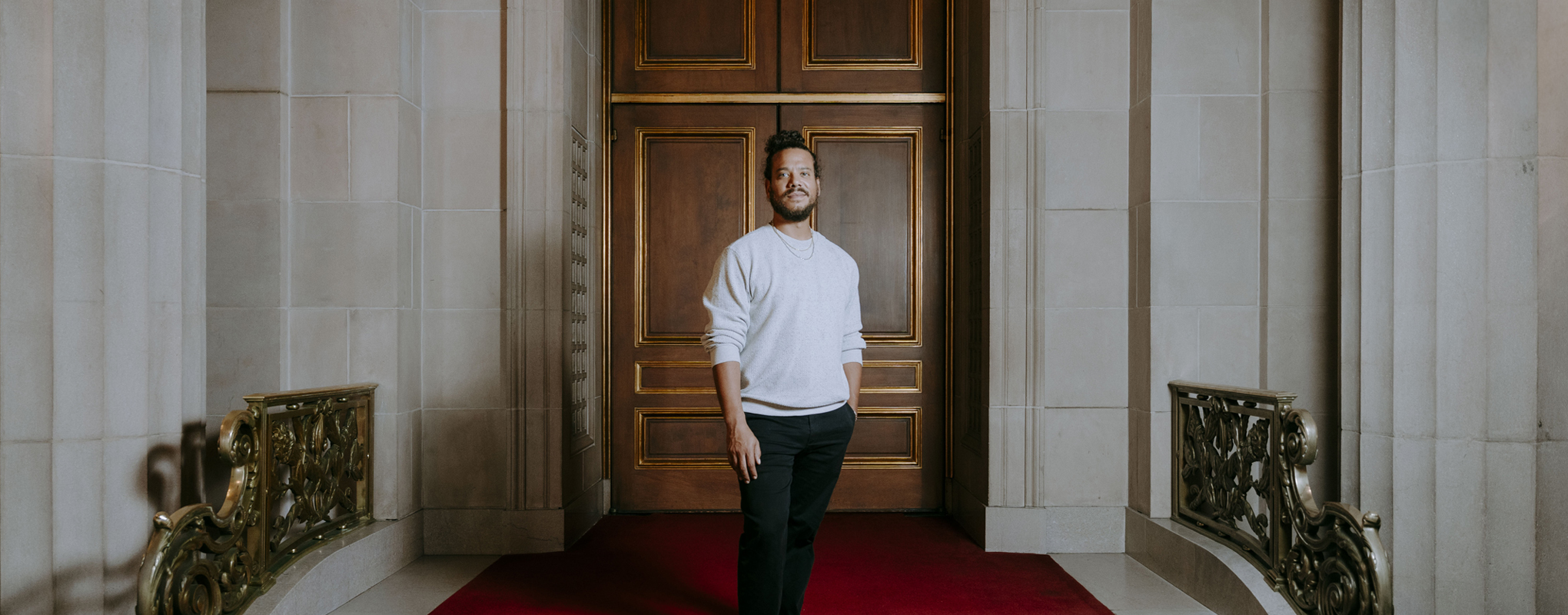 Alum Ryan M in front of a city hall doorway