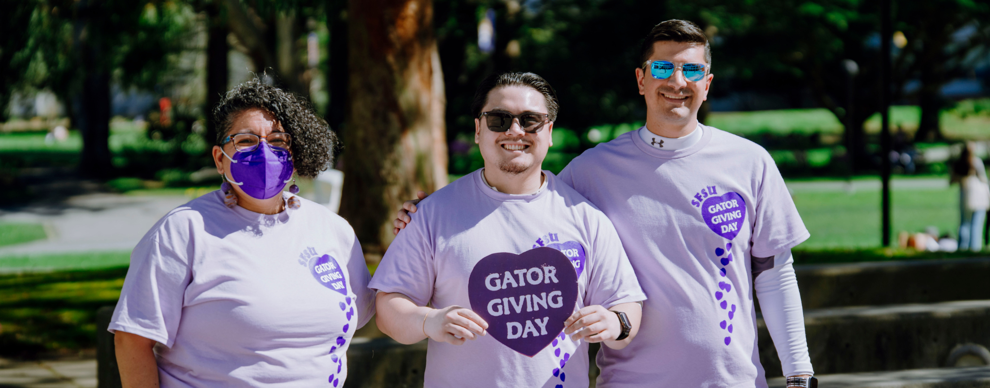 Three volunteers wearing SFSU Gator Giving Day purple tshirts
