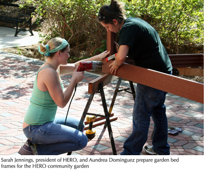 Photo of Sarah Jennings, president of HERO, and Aundrea Dominguez preparing a garden bed frame for the HERO community garden