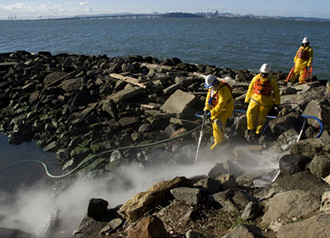 Workers use high-pressure hoses to dislodge thickening oil from rocks near the Berkeley Marina