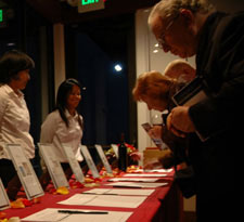 A photograph of Taste of the Bay attendees bidding on silent auction items.