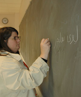 Photo of student Suzanne Levi-Sanchez writing in Persian script on a blackboard.