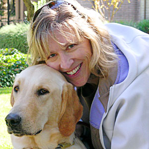Photo of student Wendy Mellberg Haecker as she hugs Carnegie, one of the guide dogs she is training.