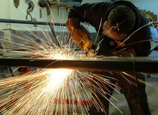 A photo of Ethan Kerber working in his warehouse, with sparks flying.
