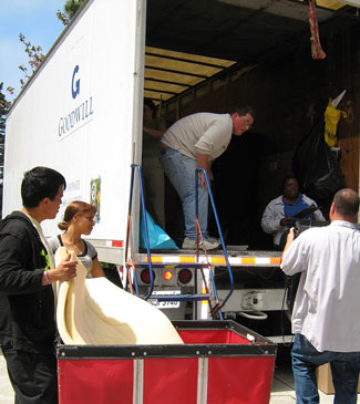 Photograph of a Goodwill collection truck with volunteers carrying items into the truck and sorting through donations.