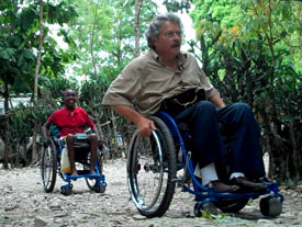 Photo of RoughRider recipient Vladimer and Whirlwind Wheelchair co-founder Ralf Hotchkiss using their wheelchairs to explore a rocky trail