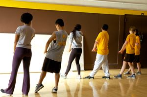 A photo of the backs of six students practicing a dance move